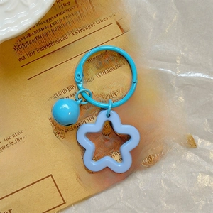 Close-up of a blue star acrylic keychain with a matching bell on a vintage newspaper background
