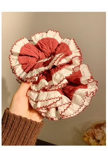 Detailed view of red and white pleated lace scrunchie with soft fabric texture