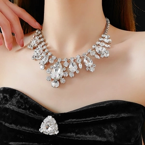 Close-up of sparkling teardrop crystal necklace and brooch set worn on model