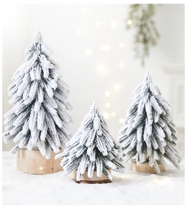 Close-up of three mini flocked snowy Christmas trees on round wooden bases for decor