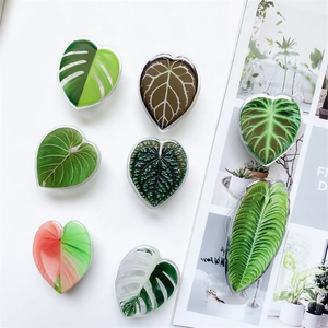 Detailed close-up of heart and leaf shaped acrylic phone grips with tropical leaf patterns