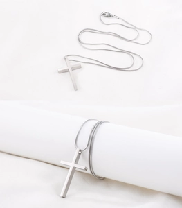Détail d'un pendentif croix minimaliste en acier inoxydable argenté et chaîne serpent