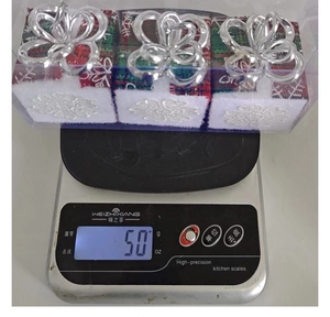 Detailed view of three plaid Christmas box ornaments weighing 50g on a digital scale