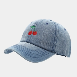 Close-up of the vintage light blue denim baseball cap featuring red cherry embroidery detail