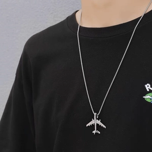 Close-up of silver airplane pendant necklace with box chain on a male model wearing black