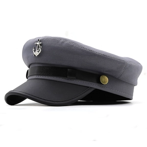 Close-up of a dark grey sailor hat featuring a silver metal anchor emblem and black brim