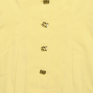 Detailaufnahme des hellgelben Kleiderstoffs mit eleganten goldenen Metallknöpfen