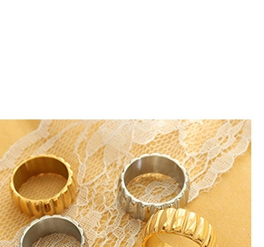 Close-up of gold and silver ribbed metal rings set on elegant lace fabric detail