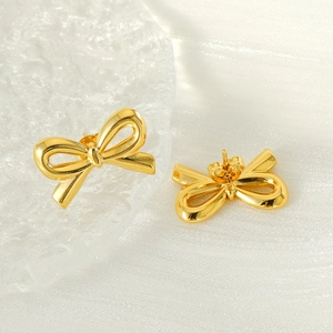 Detailed view of gold bow-shaped stainless steel stud earrings on a silk background