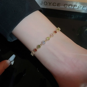 Detail shot of colorful round zircon bracelet with gold plating on a textured dark background