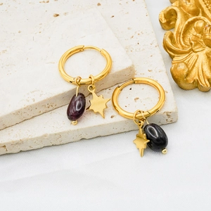 Macro detail of gold-plated star charms with natural purple stones on beige stone