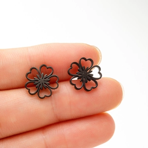 Vue détaillée des boucles d'oreilles fleurs ajourées en noir mat tenues à la main