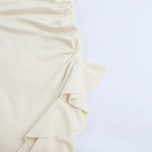 Detail view of cream ruffle dress showing pleated fabric texture and elegant stitching