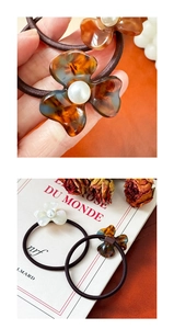 Close-up of amber and white acetate flower hair ties with pearl center on a book