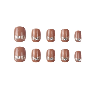 Short nude press-on nails with silver glitter bows and sparkling rhinestone accents