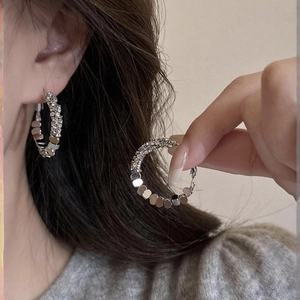 Detail view of silver geometric hoop earrings with textured finish on model