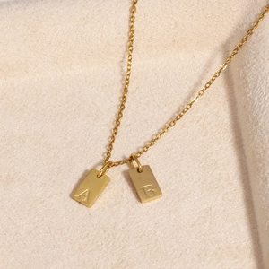 Close-up of 18k gold plated stainless steel square pendants with letters A and B