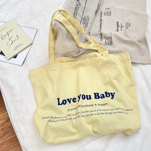 Close-up of yellow canvas tote bag with blue 'Love You Baby' text and soft texture