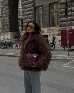 Street style view of a plush brown faux fur coat with a matching leather handbag