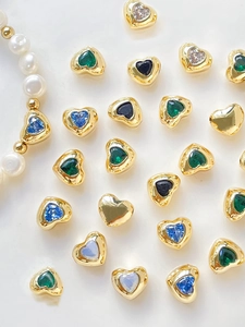 Macro detail of 14k gold heart spacers with colorful zircon stones on white background