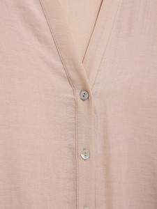Macro shot of V-neckline detail with shell luster buttons on light pink textured shirt