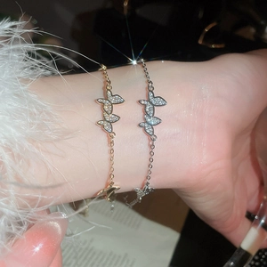 Detailed view of silver and gold zircon butterfly bracelets worn on a model's wrist