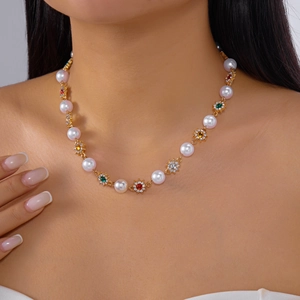 Close-up of model wearing pearl necklace with colorful rhinestones and gold flowers