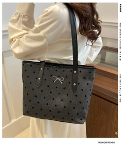 Detail der grauen Polka-Dot-Tragetasche mit Metallschleife und schwarzen Henkeln
