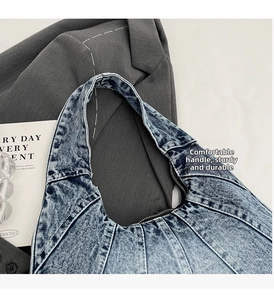 Détail rapproché du sac en jean délavé montrant la texture usée et le zip