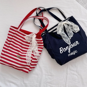 Detail of striped canvas tote bag with decorative lace bow and elegant Bonjour print