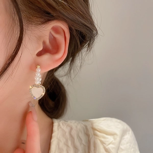 Detail of heart-shaped pearl earrings with rhinestones on a model for a stylish look