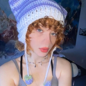 Detail of handmade purple crochet cat ear hat with decorative berry-shaped pom-poms