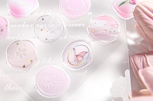 Macro detail of pink translucent wax seal stickers with gold foil and butterfly motifs