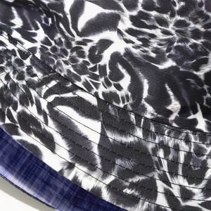Detail of graffiti print bucket hat showing leopard pattern and multi-row stitching on brim