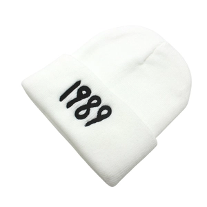 Detailed view of the black 1989 embroidery on the cuff of a white knitted beanie hat