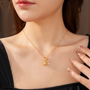 Primo piano della collana dorata a doppio ciondolo con sfera cava e croce di cristalli