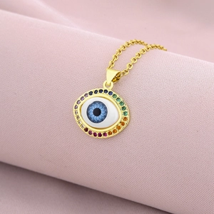 Detailed close-up of gold evil eye pendant with rainbow pavé stones on pink silk fabric