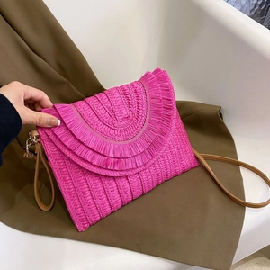 Close-up of fuchsia woven straw clutch with three-layer fringe and brown leather strap