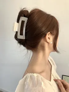 Detail of a cream-colored hollow rectangular claw clip on hair for a minimalist look