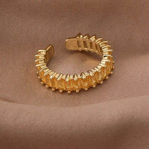Macro shot of gold square yellow zircon ring with prong setting on brown silk fabric