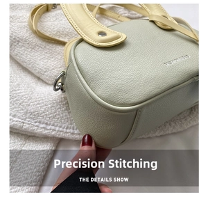 Détail rapproché du sac à main en cuir grainé montrant les coutures et le design bicolore