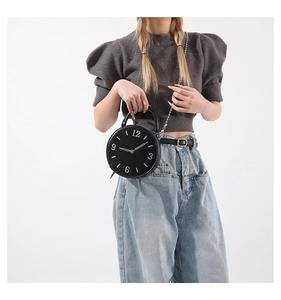 Détail d'un sac rond créatif en forme de réveil avec une bandoulière en chaîne