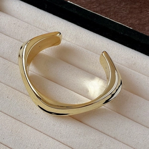 Minimalist golden wavy irregular open bangle bracelet with high mirror finish on velvet tray