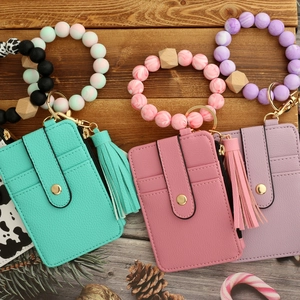 Three leather wristlet wallets with silicone beads and tassels on a festive background