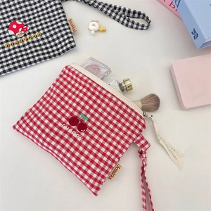 Detail of embroidered checkered pouches with cosmetics and a wrist strap for storage