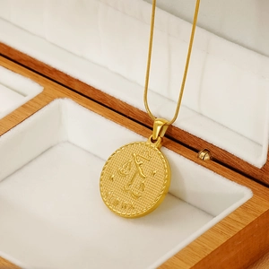 Close-up of 18K gold Libra constellation pendant with snake chain on jewelry box