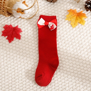 Detail of red Christmas baby sock with bow and tiny stocking charm on cozy knit