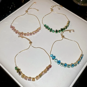 Détail de quatre bracelets en zircone réglables colorés sur un présentoir à bijoux