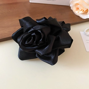 Vue détaillée de la texture des pétales de rose en satin noir de cette pince à cheveux