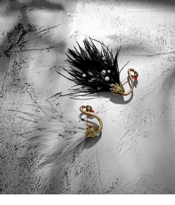 Close-up of black and white swan brooches featuring delicate feathers and pearls